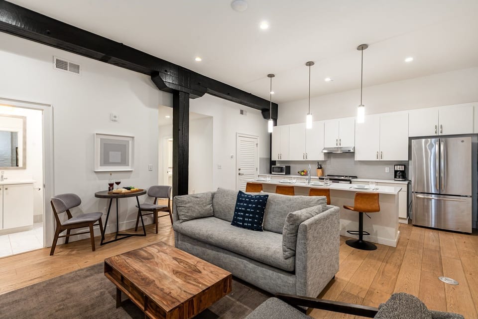 Unit 2: Open-concept living area featuring cozy furnishings, smart TV, small dining area with seating for 2 guests, and a sleeper sofa.