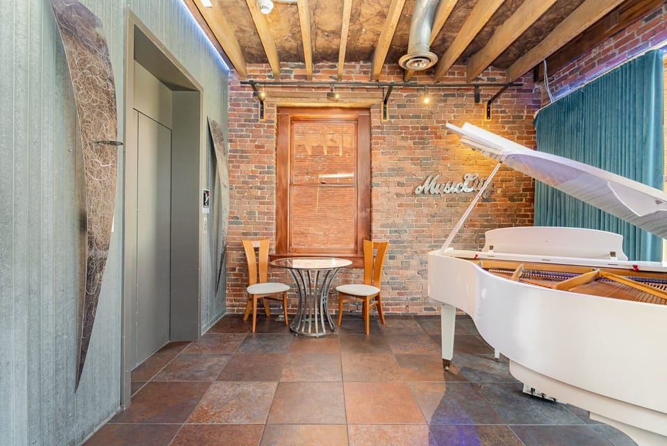 Unit 2: Main Living Area featuring designer furnishings, TV Projector, piano, electric guitars, and electronic Window Curtains