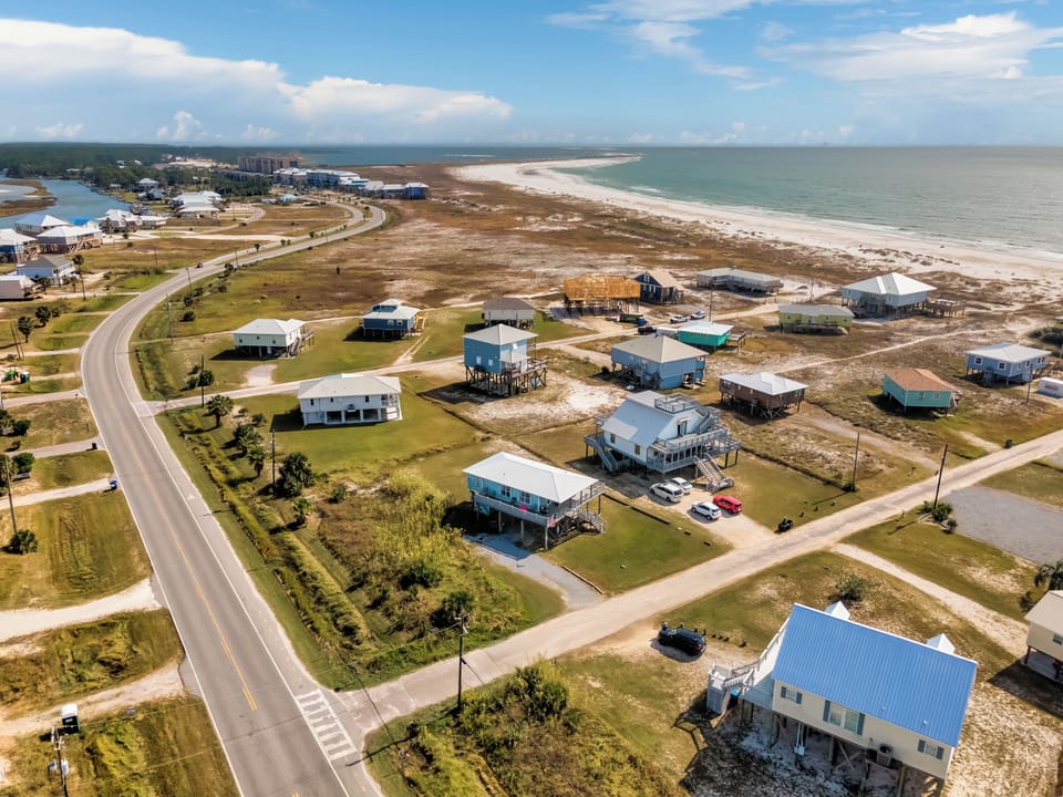 Coastal community stretches along pristine shoreline with vacation homes positioned near sandy beaches and clear waters.