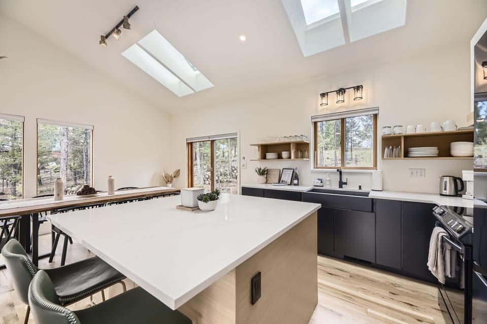 Your gourmet kitchen features soaring ceilings with skylights, sleek countertops, and forest views that create a bright, inspiring space for cooking.