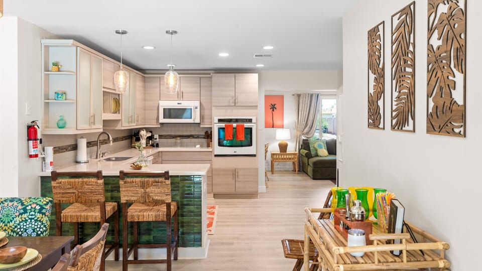 A seamless flow from kitchen to living with mid-century island flair, bamboo bar cart, and warm wood textures