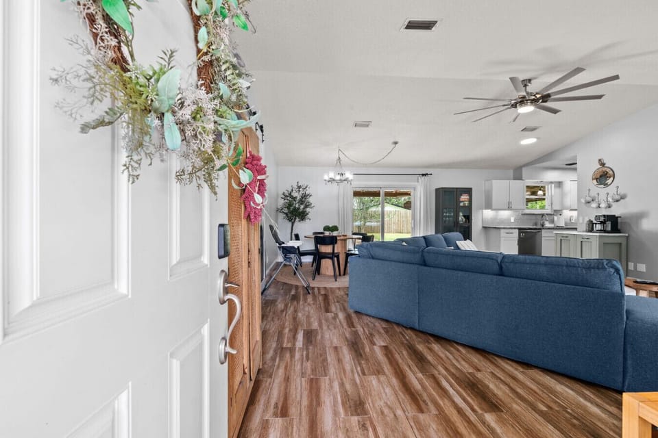 Open-concept living room with plush sectional, Smart TV, and direct access to the outdoor lounge and pool through sliding doors.