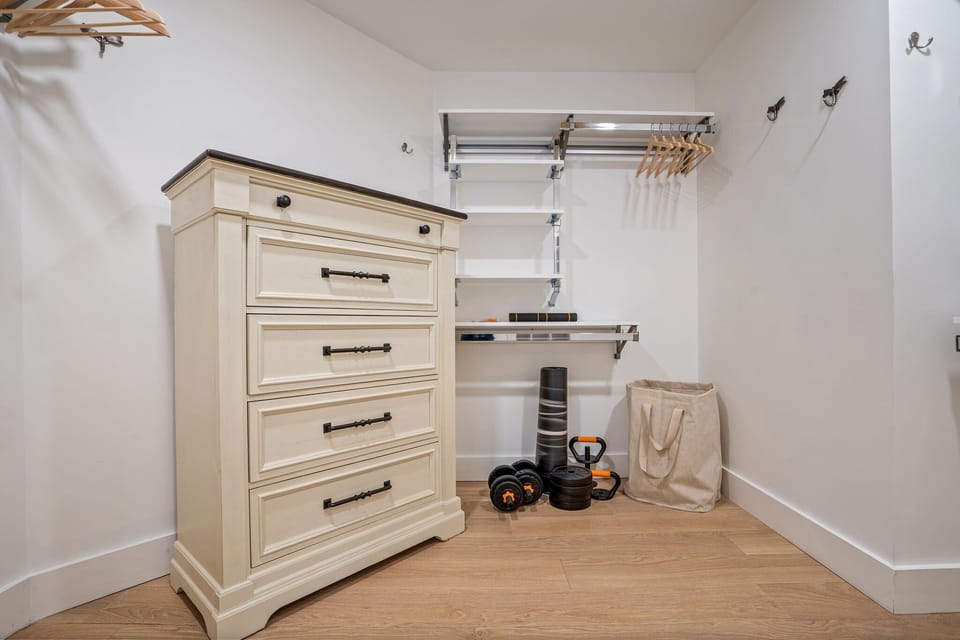 Stylish walk-in closet with storage, hanging rods, and workout gear.