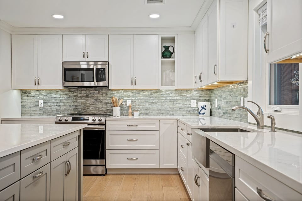 Bright kitchen with white cabinets, textured backsplash, and appliances. 