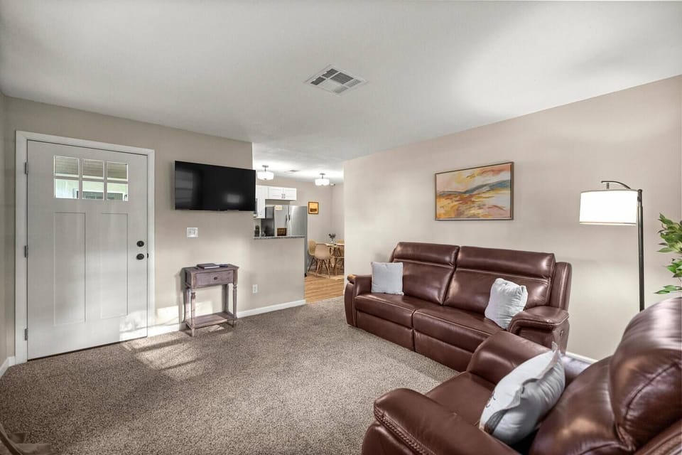 Cozy living room with leather sofa, smart TV, and open layout to kitchen and dining area