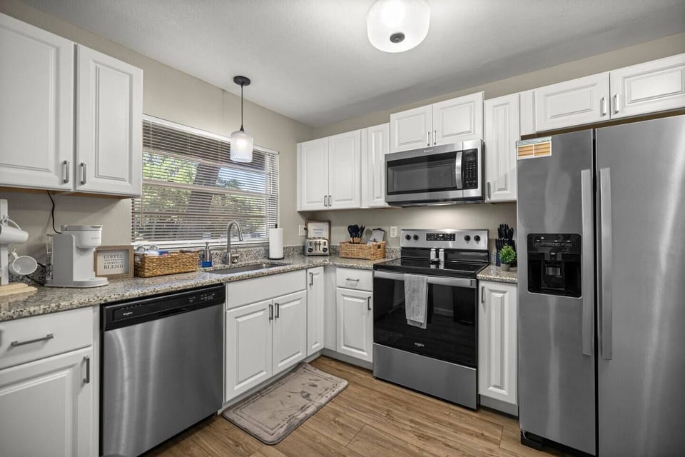 Clean, modern kitchen with full appliances, coffee station, and warm wood flooring throughout