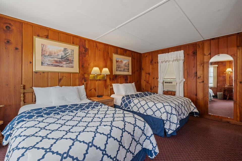 Warm wood paneling and soft lighting frame two double beds, offering a comfortable and inviting place to rest after a day in the mountains.