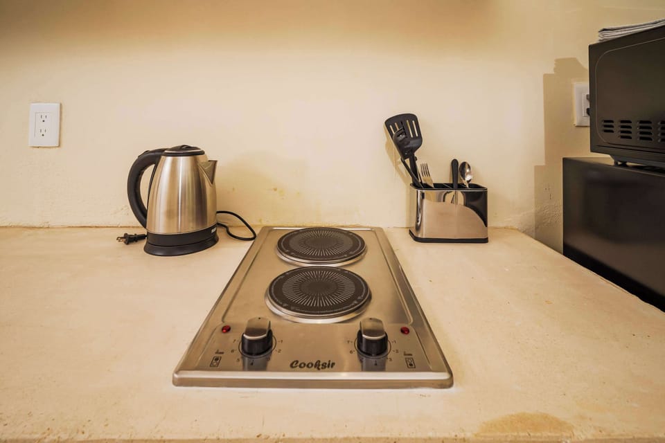 Hervidor de agua asi como estufa y utencilios de cocina.