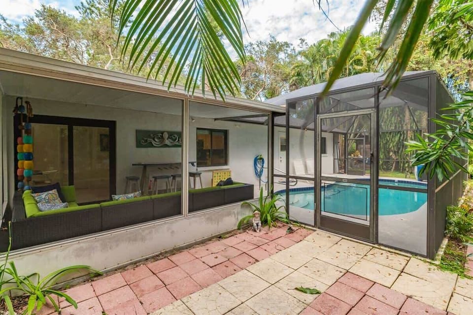 Peaceful home tucked in lush greenery with a private screened pool, covered patio lounge, and spacious driveway