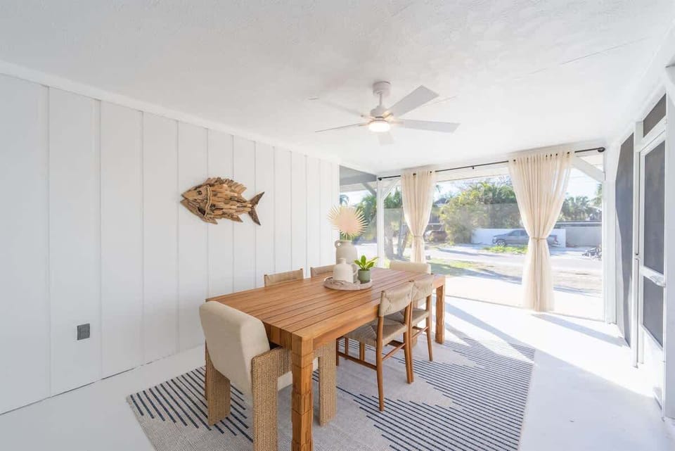 The kitchen features stainless steel appliances, granite countertops, a double-door fridge, built-in microwave, and ample white cabinetry. An open layout flows into the dining and patio areas.
