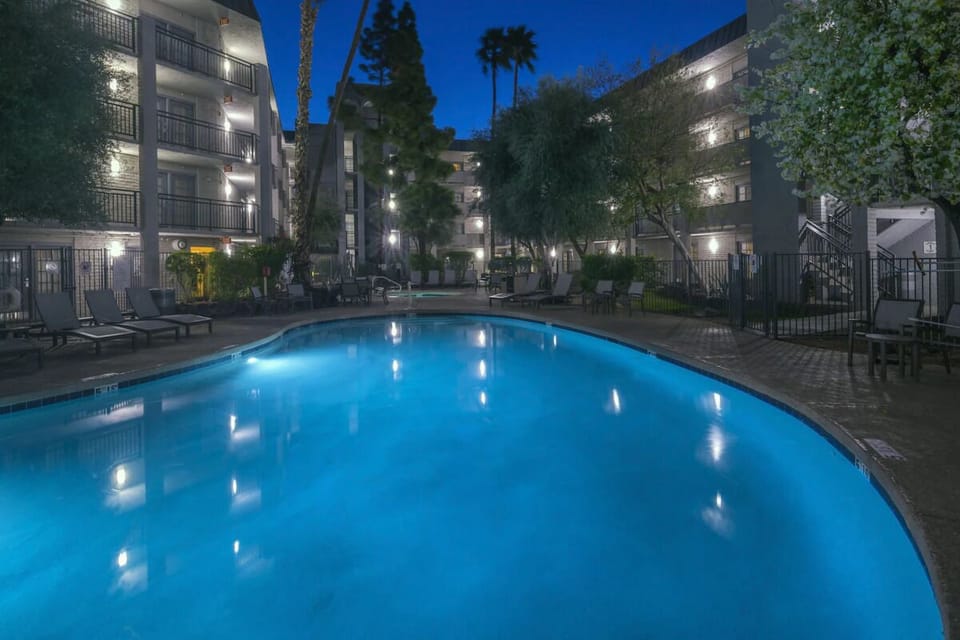 Swim at dusk in a glowing pool surrounded by palms.