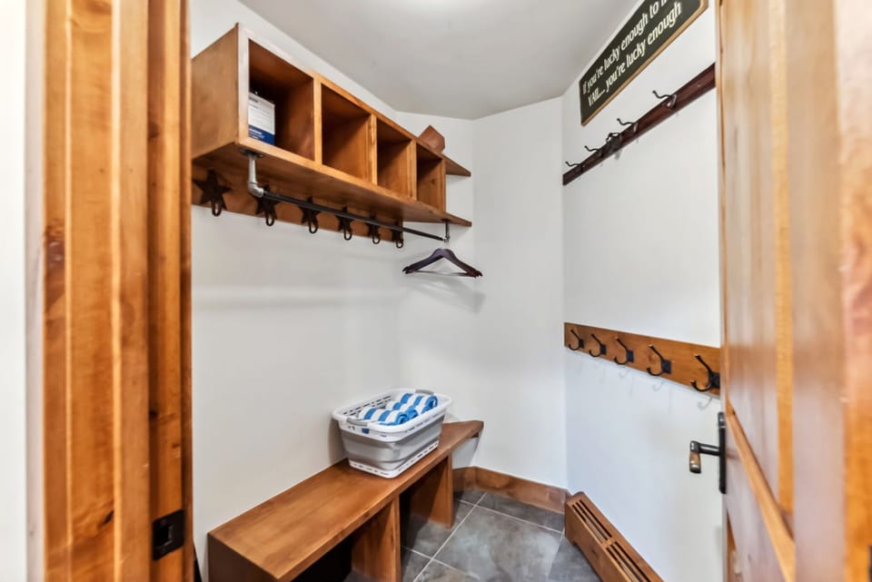Small mudroom with a wooden bench, shelves, and coat hooks.