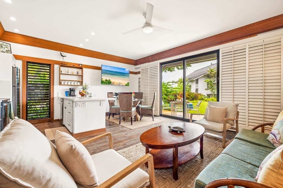 Open-concept living and dining space with tropical decor, natural light, and a fully equipped kitchen for easy vacation meals.