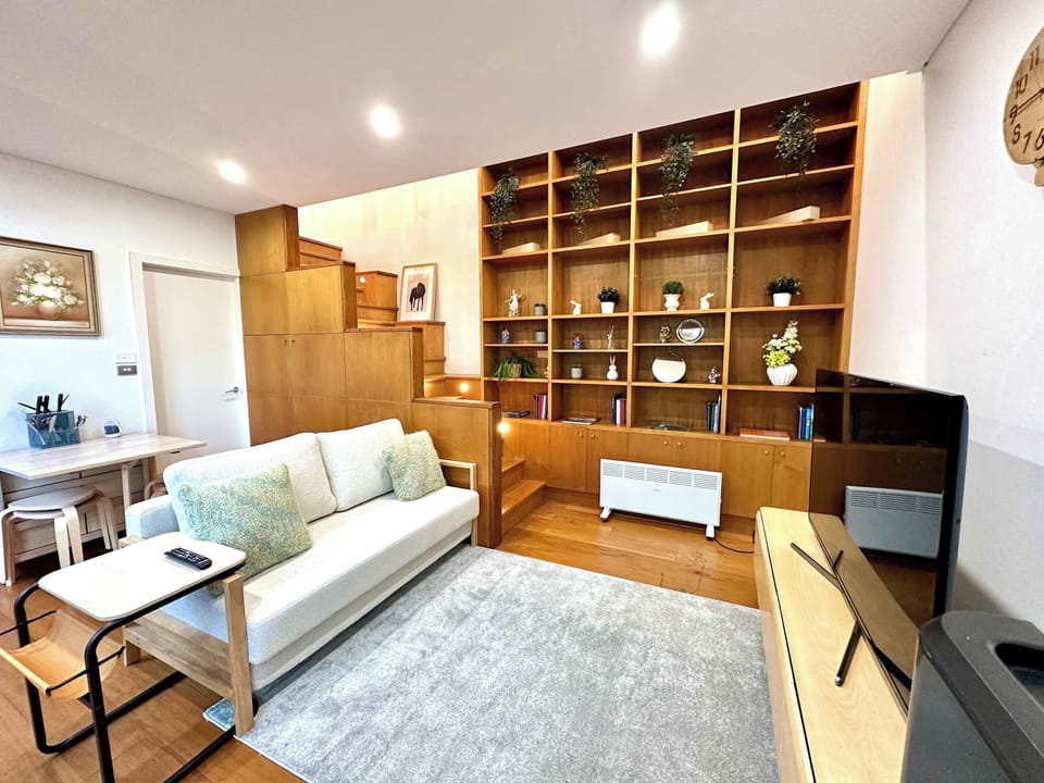 Living area with built-in shelving, sofa seating, and warm timber flooring.