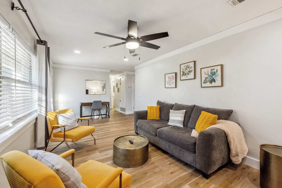 The vibrant pops of yellow and elegant gold accents provide a cheerful, upscale feel, while the large windows flood the space with natural light. It’s the ultimate spot to unwind during your stay.