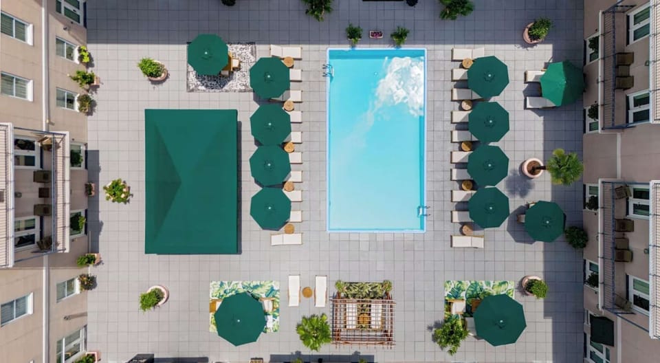 Aerial view of a pool with green umbrellas and lounge chairs