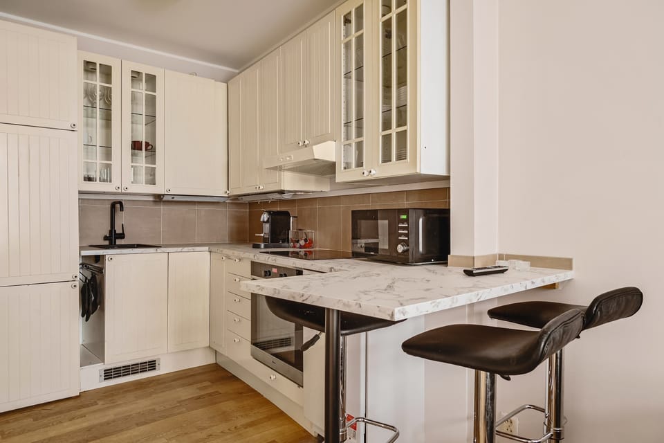 Functional kitchen with ample cabinet storage, a sleek marble countertop, and a convenient breakfast bar for quick meals or coffee breaks.