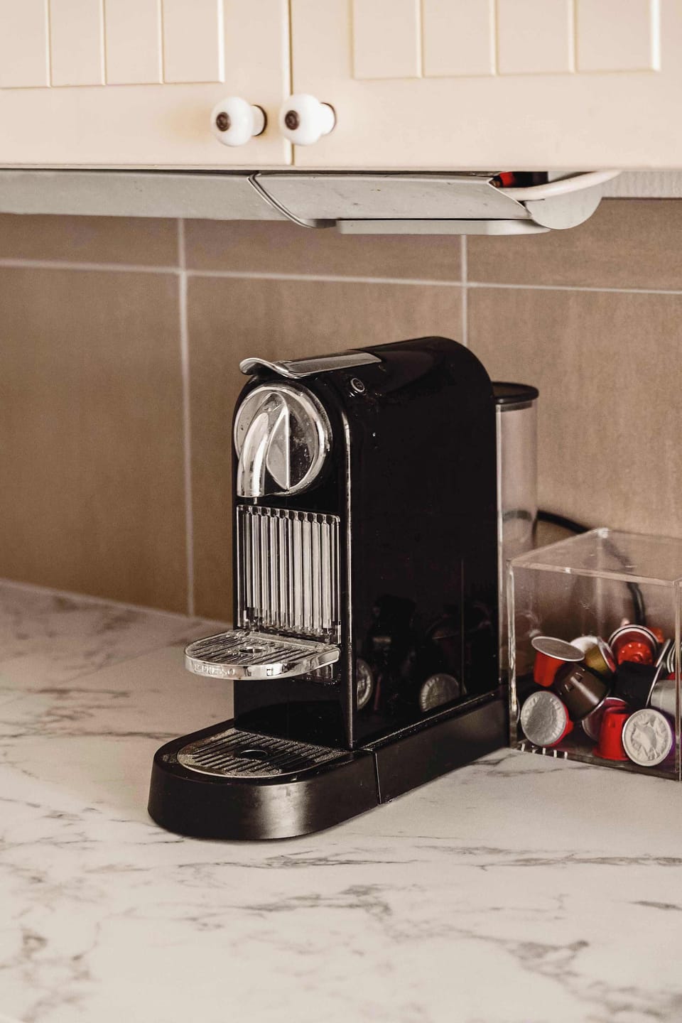 A stylish black coffee machine with an assortment of coffee pods, ready for your morning boost. Enjoy fresh coffee at your convenience.