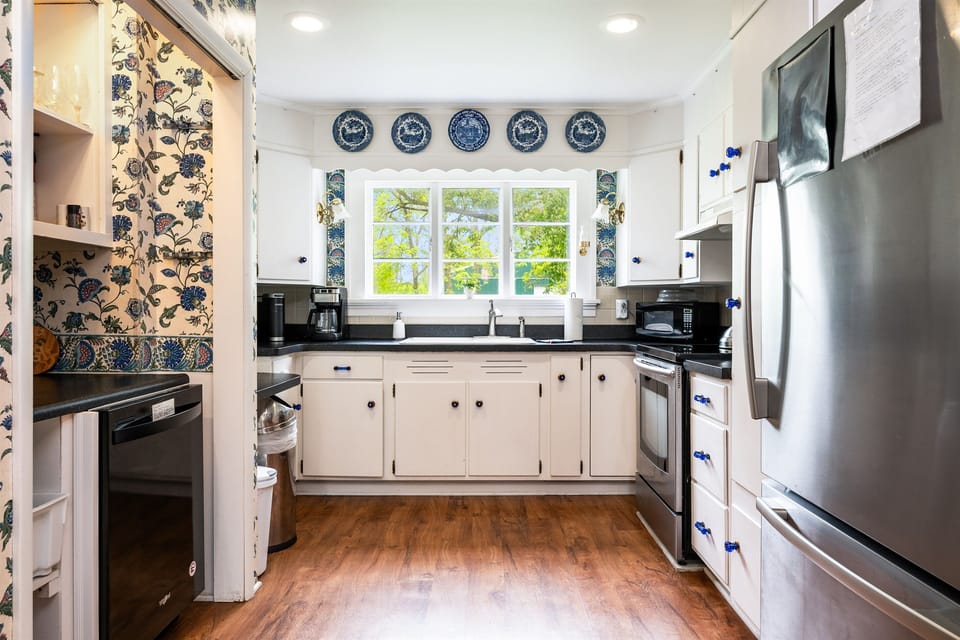 Charming vintage kitchen with modern stainless steel appliances, classic blue accents, and a scenic view above the sink 🌿🍽️💙