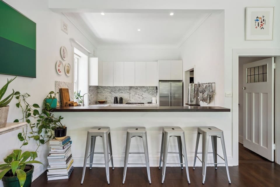 The long breakfast bar with stools invites morning coffee rituals and casual bites throughout the day.