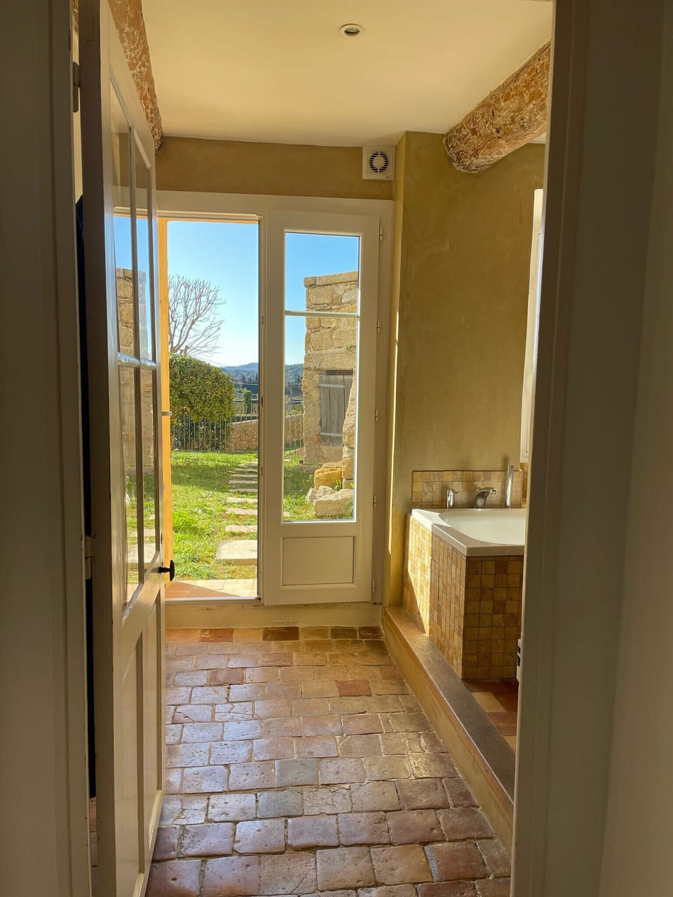 This spacious bathroom opens directly onto the garden, offering a rare experience between indoor comfort and nature. Perfect for relaxing in the sun, it combines rustic charm, terracotta floors and soft light.