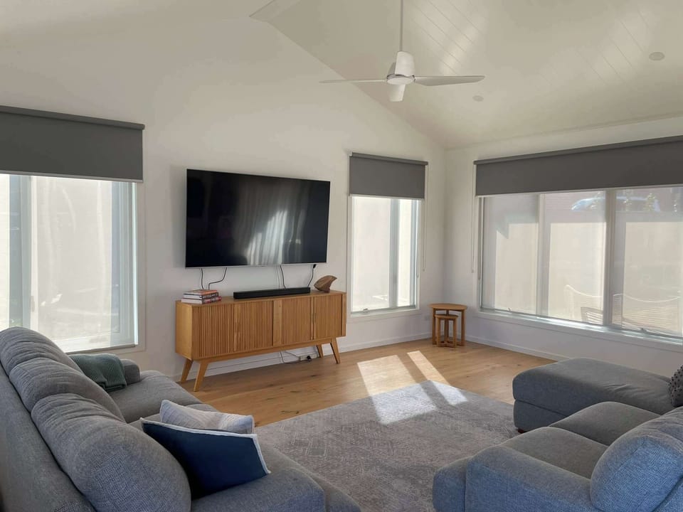 Large living room with high-ceilings, flat screen TV, fan and heating. 