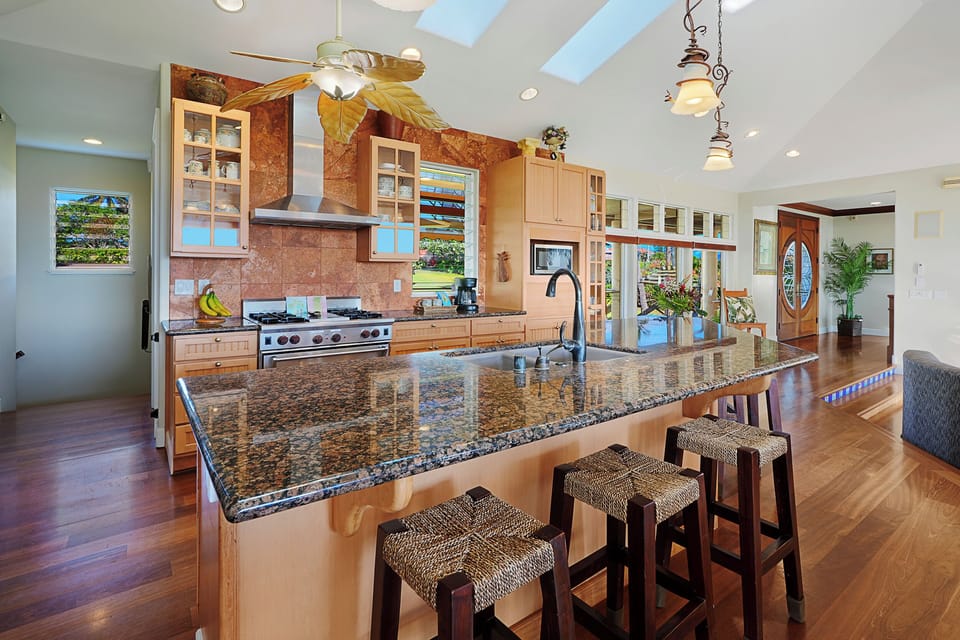 Spacious sunlit kitchen, granite island, bar stools, stainless, wood, skylights