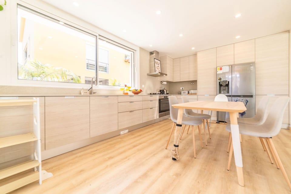 Modern open-plan kitchen and dining area with light wood cabinetry — Villa Aroeira Village, luxury holiday villa in Aroeira