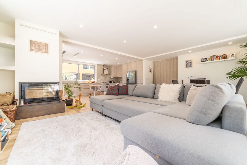Bright open-plan living room with fireplace and grey sectional sofa — Villa Aroeira Village, luxury holiday villa in Aroeira