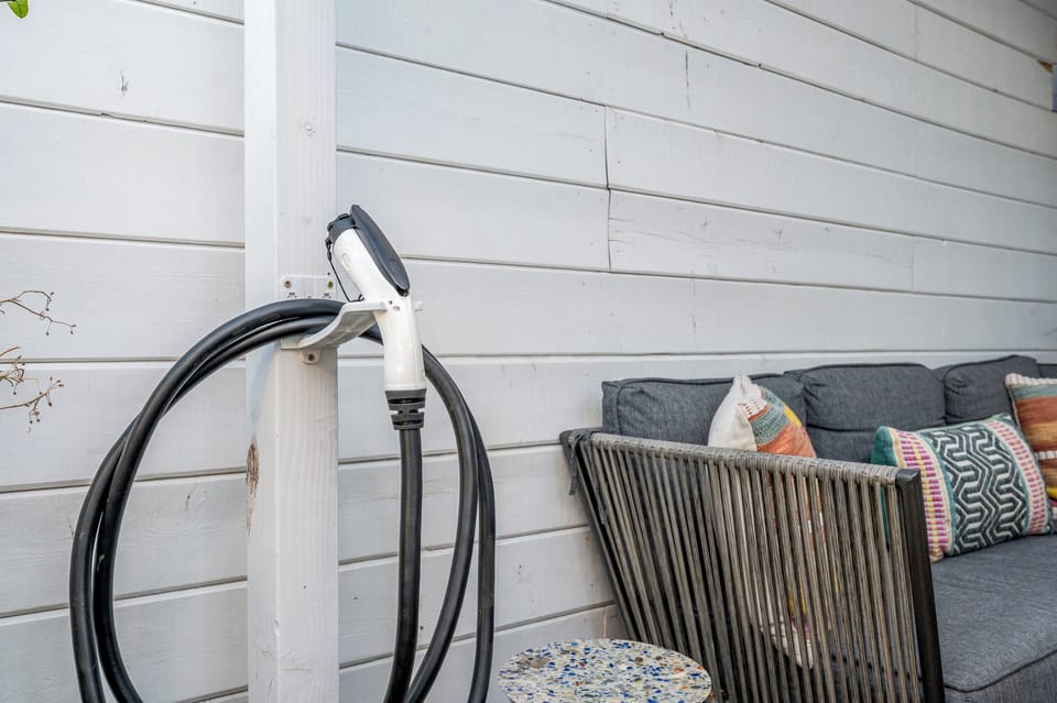Outdoor EV charger station beside cozy patio furniture with colorful cushions