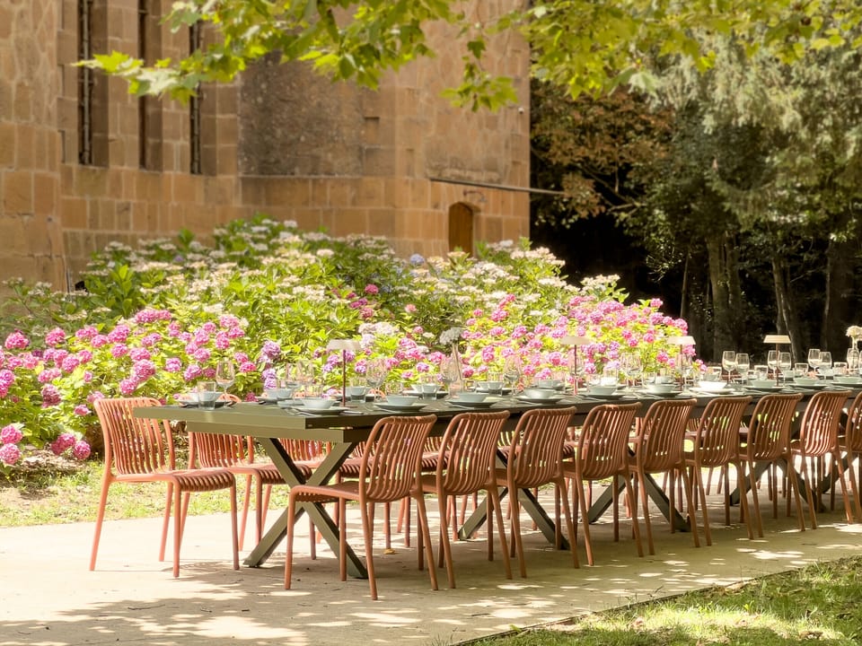 Chapel garden - Exterior - Long outdoor table set for large group dining with blooming hydrangeas and the castle chapel as backdrop — perfect for retreat dinners.