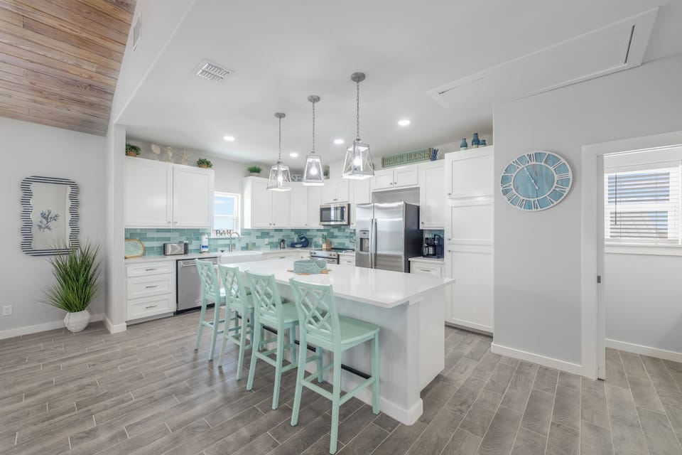 Cook together in this bright, coastal kitchen with modern appliances and cheerful mint seating at your spacious island.