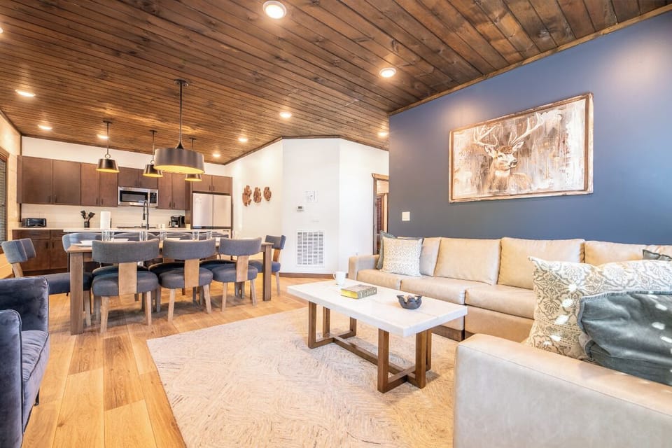 Relax in your open-concept living space with soaring wood-planked ceilings, cozy seating, and a modern kitchen ready for gathering. Mountain charm meets modern comfort in every detail.