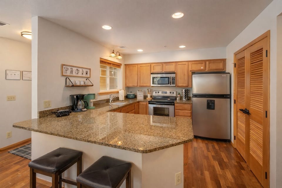 This fully equipped kitchen features granite countertops, stainless steel appliances, and breakfast bar seating for convenient meal prep and casual dining.