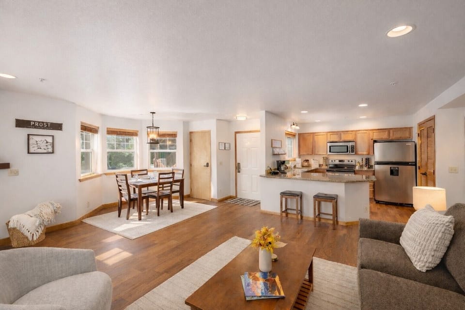 The spacious open-concept living space with warm wood floors, granite counters, and cozy furnishings is perfect for memorable gatherings.
