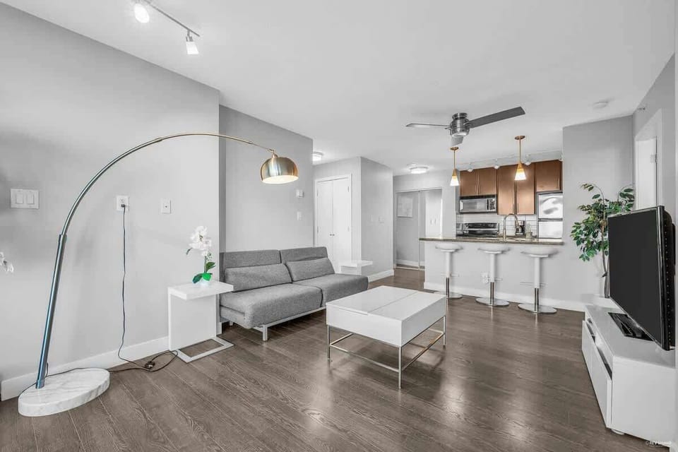 Modern and stylish open-concept apartment with sleek hardwood floors, contemporary furnishings, and a chic kitchen featuring stainless steel appliances—perfect for urban living.