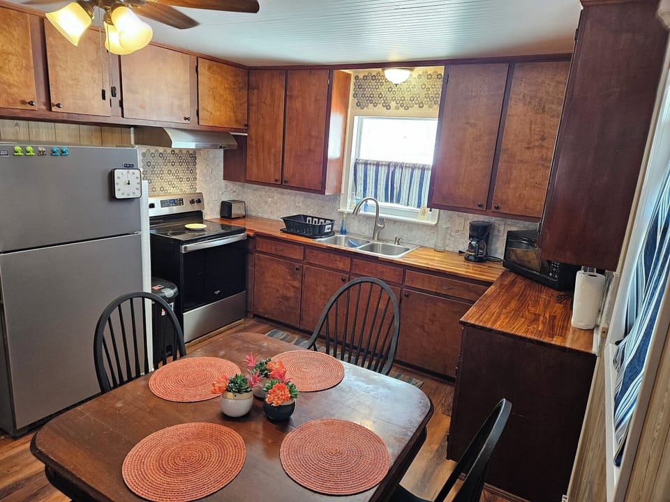 The kitchen includes a fridge, microwave &  stove, dishes & pans and coffee pot.