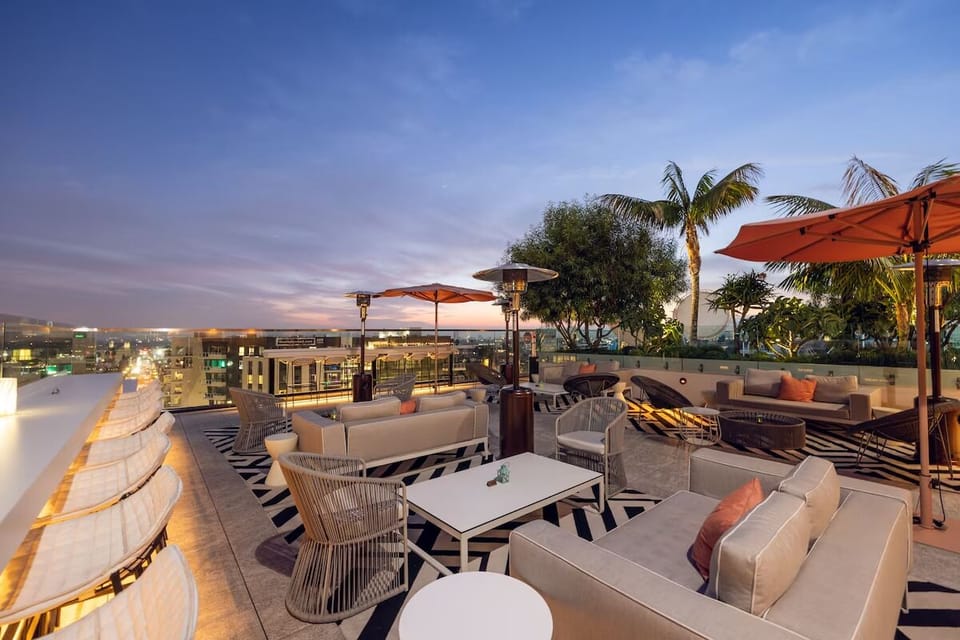 Sip at sunset as the rooftop glows above the city.