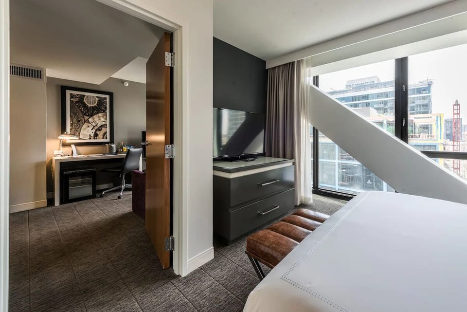 Unwind in a sunlit bedroom with city-view serenity.