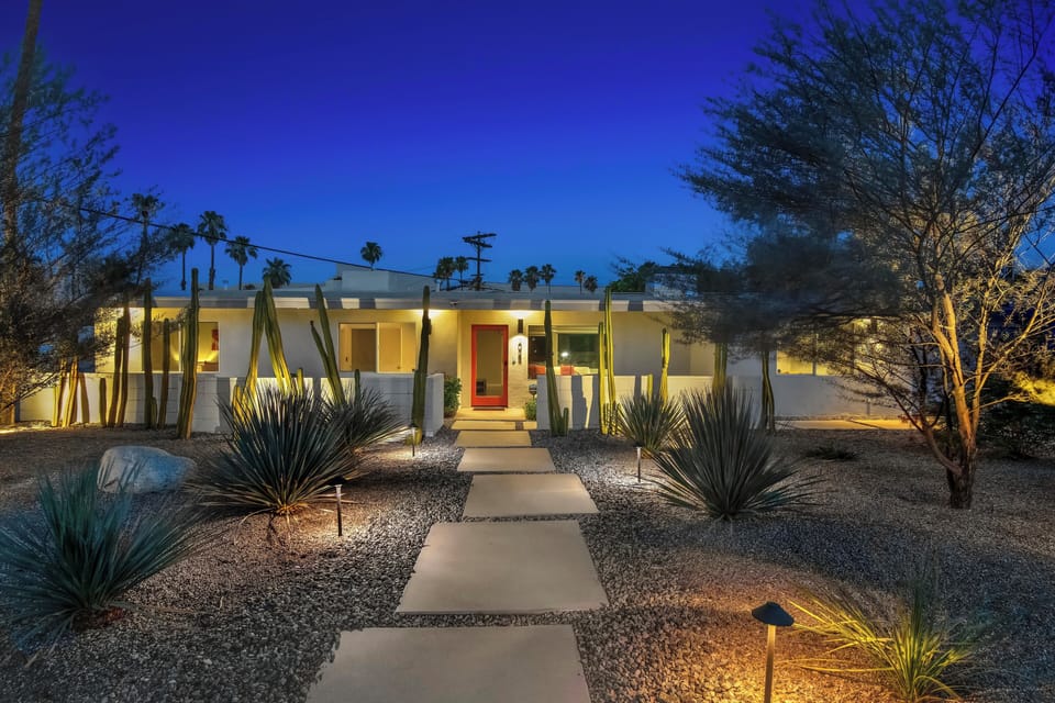 Mid-century exterior with desert landscaping and illuminated entry path