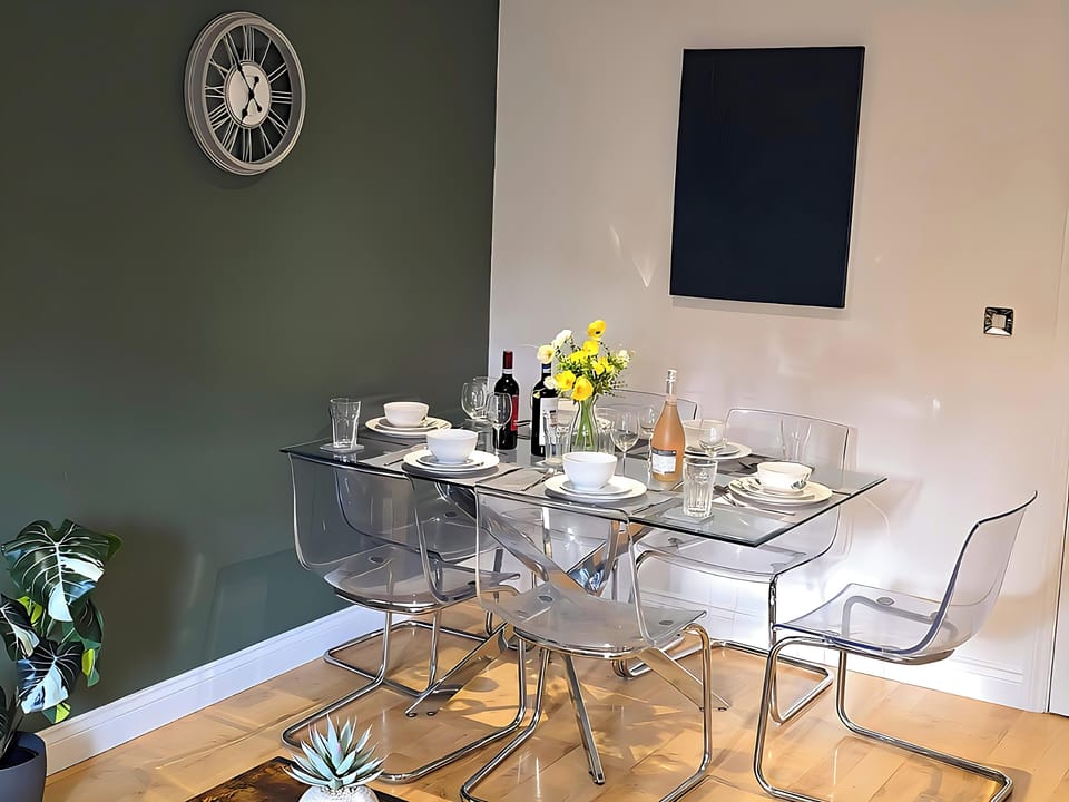 A beautifully furnished living room with comfortable sofas, a workspace with a table lamp, a 50-inch smart TV to entertain you with your favourite programmes on Virgin TV, super-fast internet, and a dining area