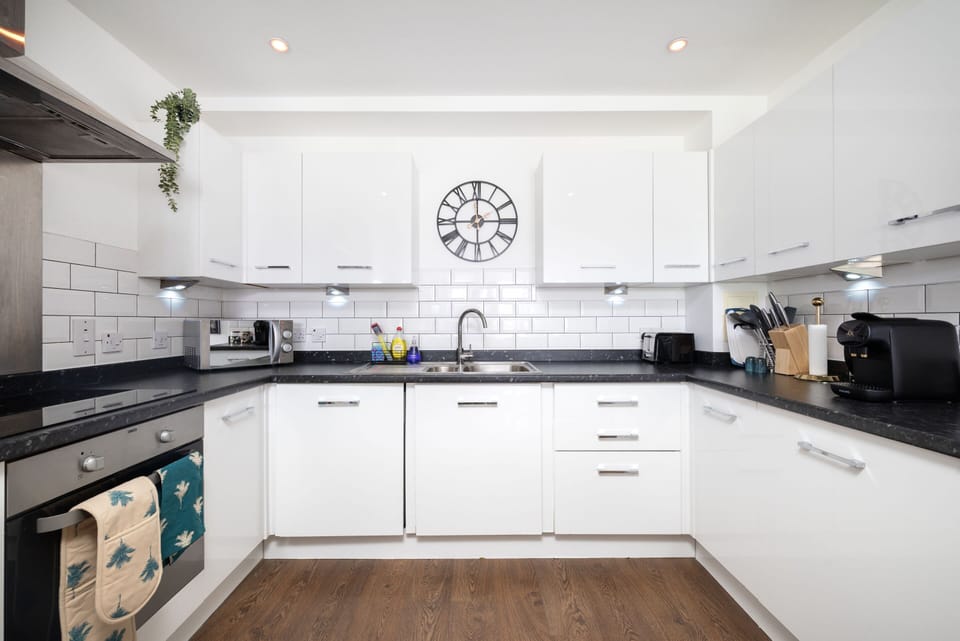 Sleek countertops, a built-in microwave, bright white cabinetry, and generous counter space make this kitchen both stylish and functional for guests.