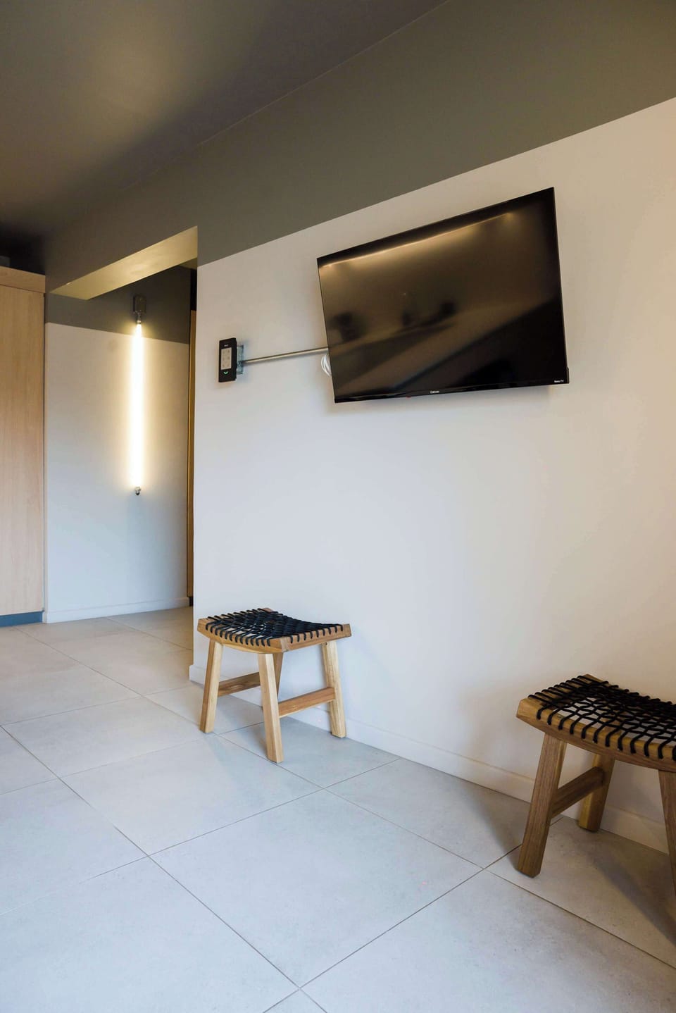 Modern and minimalist living area with a sleek wall-mounted TV and stylish seating, perfect for relaxation.