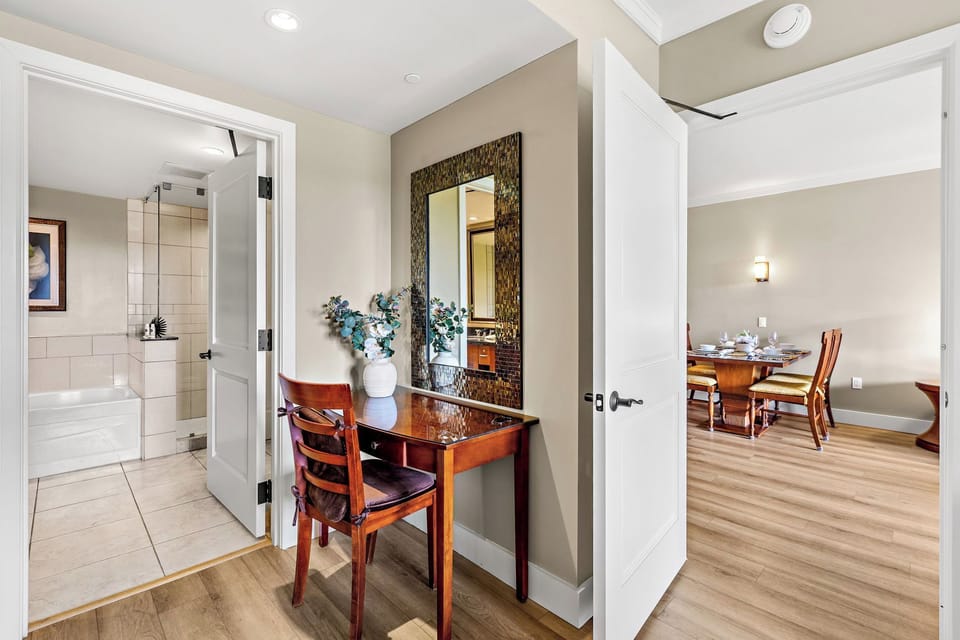 Step into your elegant workspace featuring a polished wood desk and decorative mirror, perfectly positioned between your private bathroom and dining area.