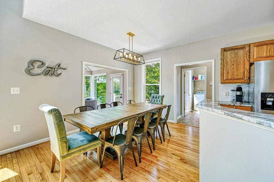 Dining Room - Alternate view of the farmhouse table with kitchen pass-through and sunroom entry visible.