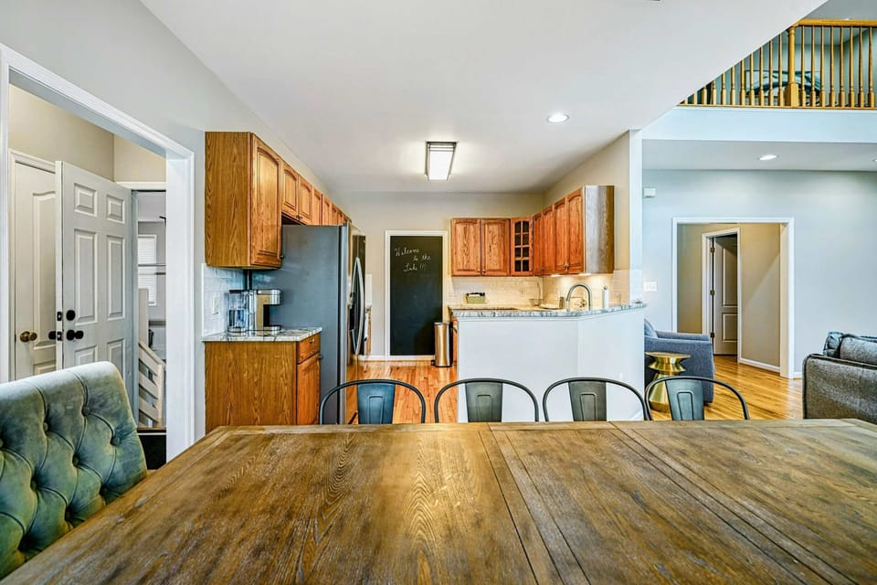 Kitchen - Dining table view into the kitchen with oak cabinets, chalkboard wall, granite peninsula, and loft above.