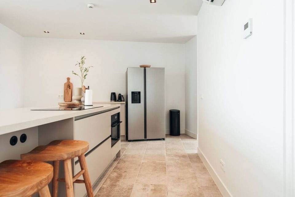 A minimalist kitchen with sleek cabinetry, a stylish island, and high-end stainless steel appliances. The neutral tones and clean lines create a sophisticated and functional space.