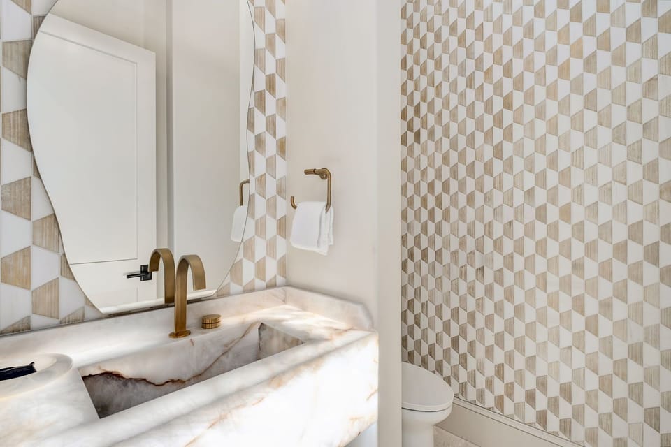 Refresh in your private bathroom featuring elegant marble countertops, designer geometric tiles, and warm brass fixtures for a luxurious touch.