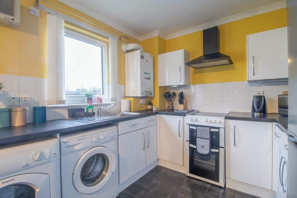 Fully equipped kitchen with modern appliances, cookware, and utensils for convenient home cooking during your stay.