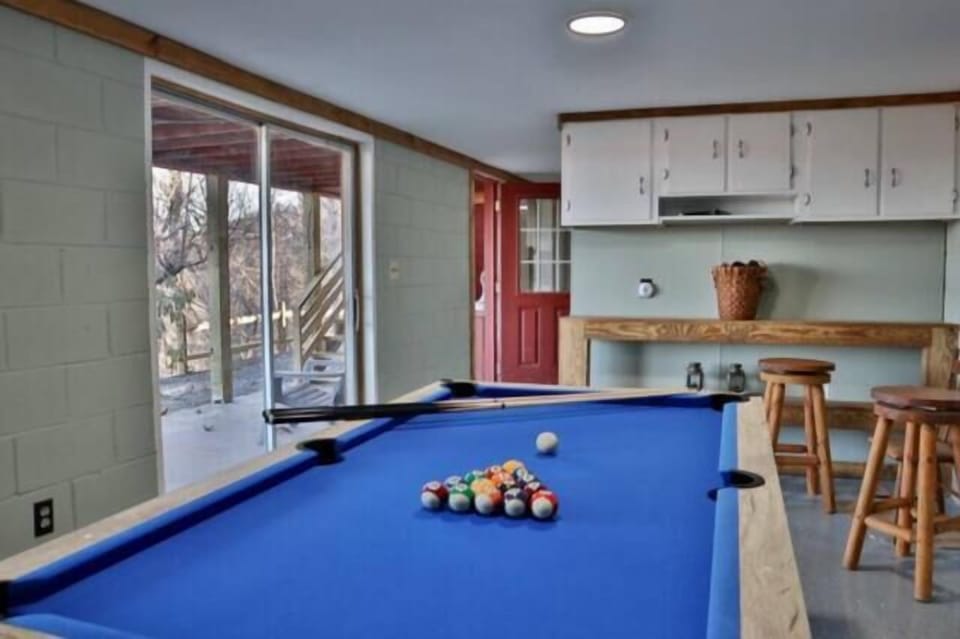 The lower-level game room includes a pool table, bar seating, and walkout access to the outdoors. This recreation area offers additional entertainment space near the Smoky Mountains.